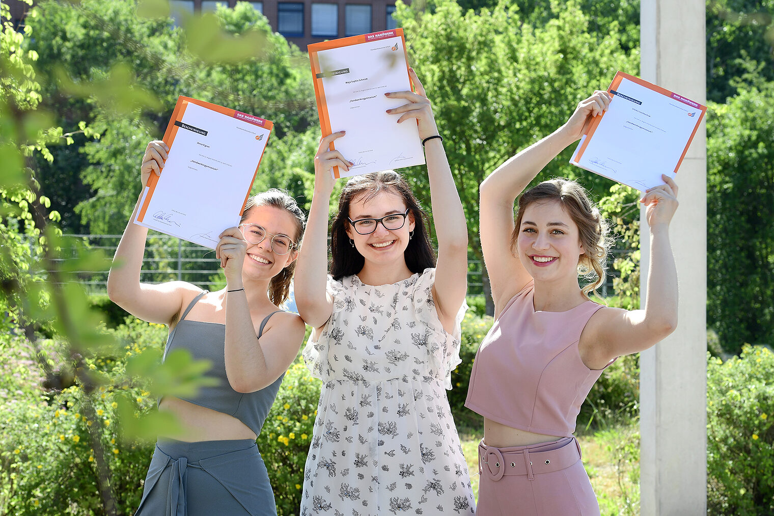 v.l.n.r. Anna Eigner, Maja Sophie Schmidt und Vivian Lischtschuk halten Ihre Bescheinigungen, die ihnen die Teilnahme an den Schulungen zu Teil III und Teil IV der Meisterprüfung bestätigen in die Luft.